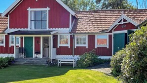 A red two-story house with a white porch, a green door, and a small bench. - 4 Star Holiday Home in Ellos (Ellos)