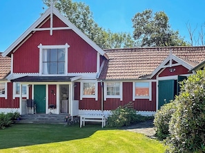 A red two-story house with a white porch, a green door, and a small bench. - 4 Star Holiday Home in Ellos (Ellos)