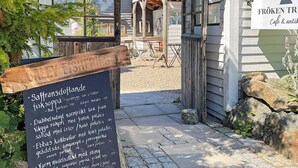 A wooden signboard with text, a building entrance, and a clear sky. - 4 Star Holiday Home in Ellos (Ellos)