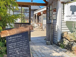 A wooden signboard with text, a building entrance, and a clear sky. - 4 Star Holiday Home in Ellos (Ellos)