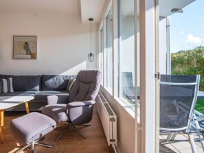 Una sala moderna con un sofá, un sillón, un reposapiés y una mesa.