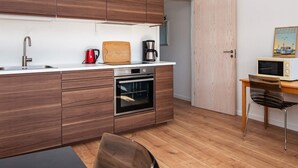 A modern kitchen with wooden cabinets, a stainless steel sink, a red kettle, a coffee maker, and a microwave on a wooden table. - 4 Star Holiday Home in Ringkobing (Ringkobing)