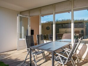 A patio with a table and chairs, a sliding glass door, and a view of a kitchen area. - 4 Star Holiday Home in Ringkobing (Ringkobing)