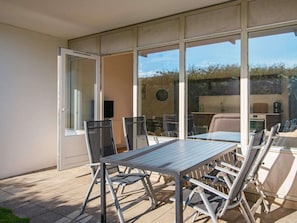 Un espace patio avec une table et des chaises, une porte-fenêtre coulissante et une vue sur l’extérieur.