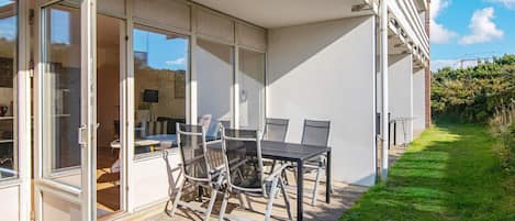 Un patio moderno al aire libre con un comedor de vidrio, una mesa y sillas.