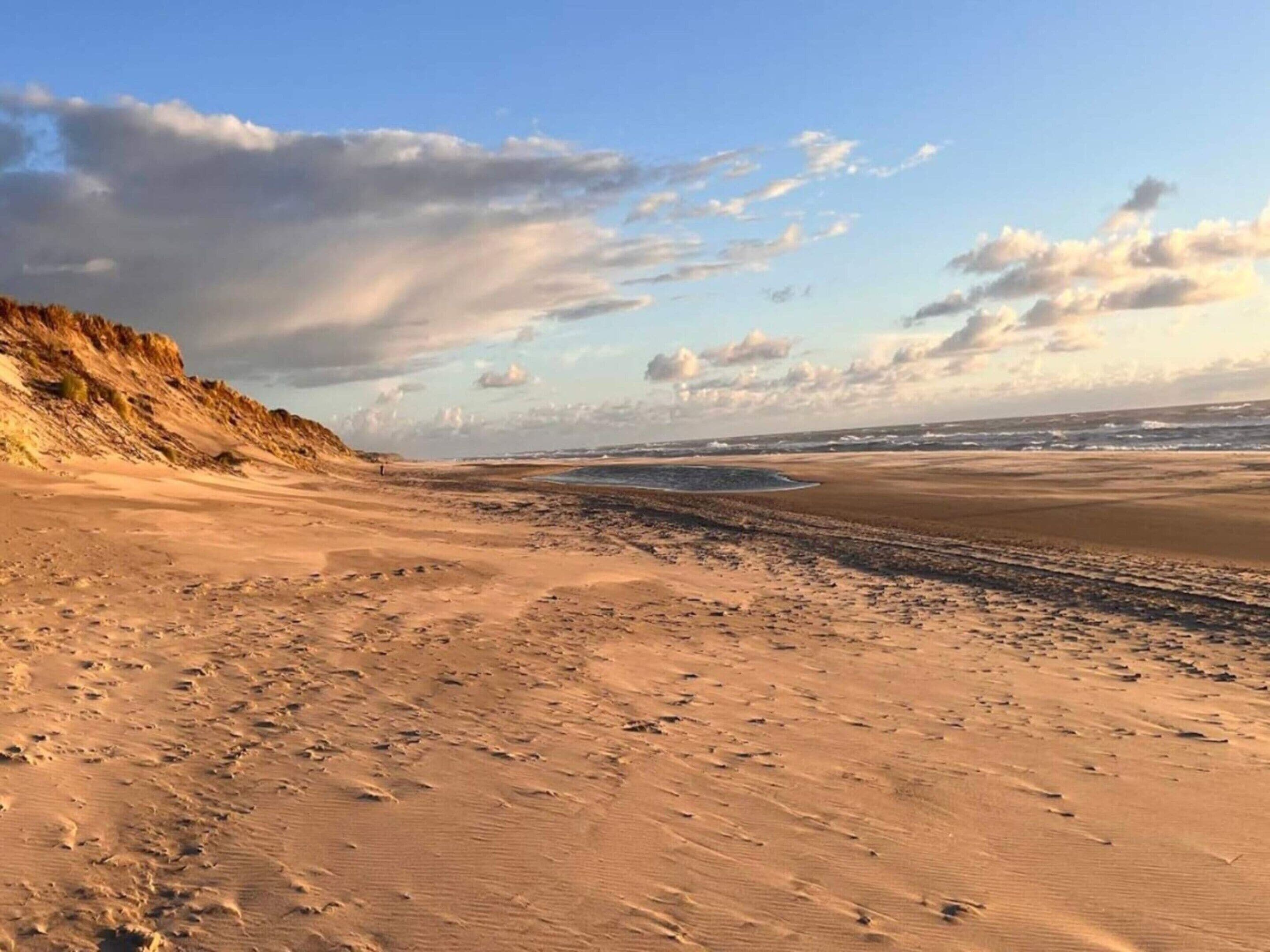 A sandy beach with dunes and a clear sky.
