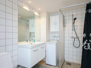 Une salle de bain moderne avec un meuble-lavabo blanc, un grand miroir, une douche avec une porte en verre et un rideau de douche noir.