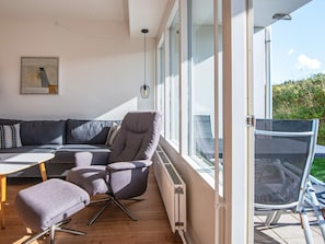 A modern living room with a sofa, armchair, ottoman, and a table.