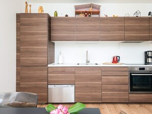 Una cocina moderna con armarios de madera, lavavajillas, horno y cafetera.