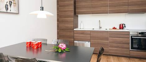 A modern kitchen with wooden cabinets, a stainless steel sink, and a dining area with a table and chairs.