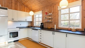 A modern kitchen with wooden walls, white cabinets, a black countertop, and two pendant lights. - 5 Person Holiday Home in Hals (Hals)