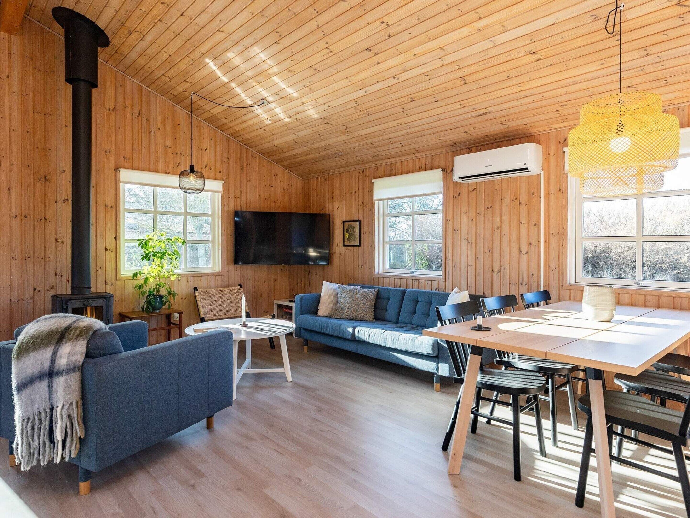 En mysig stuga med träpanel på väggarna, en soffa, ett matbord och en tv.
