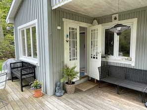 A covered porch with a seating area, a potted plant, and a Buddha statue. - 4 Person Holiday Home in Ronneby (Ronneby)