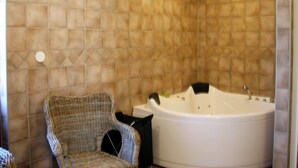 A bathroom with a bathtub, a wicker chair, and a tiled wall. - 4 Star Holiday Home in Salen (Salen)