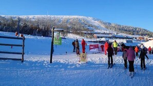 A snowy ski slope with skiers, a wooden fence, and a signpost. - 4 Star Holiday Home in Salen (Salen)