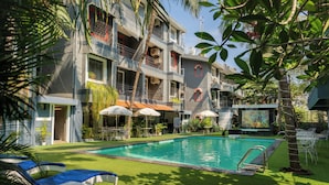 A hotel with a swimming pool, outdoor seating, and lush greenery. - Magnum Resorts Candolim (Candolim)