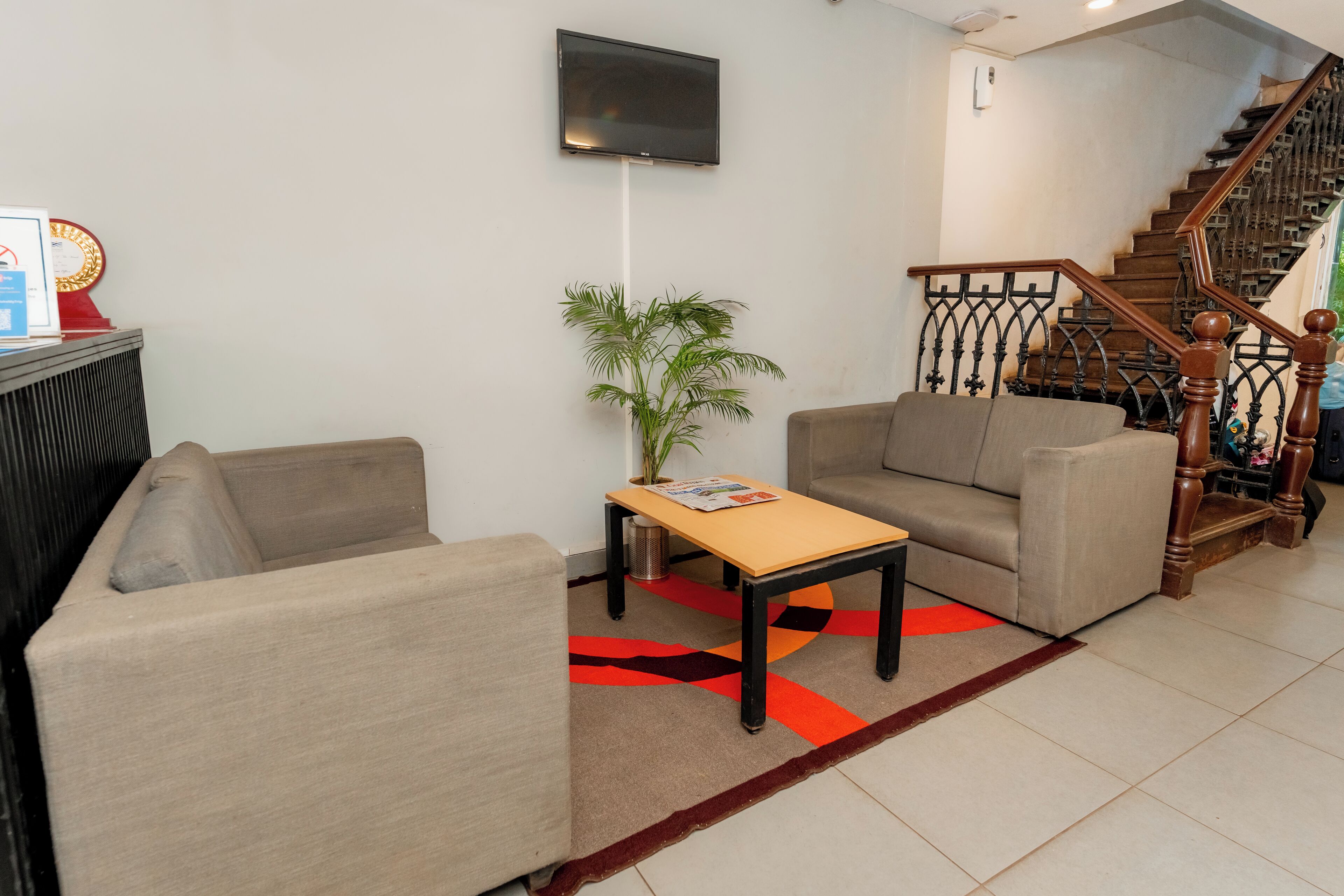 A living room with two sofas, a coffee table, a TV mounted on the wall, and a staircase.