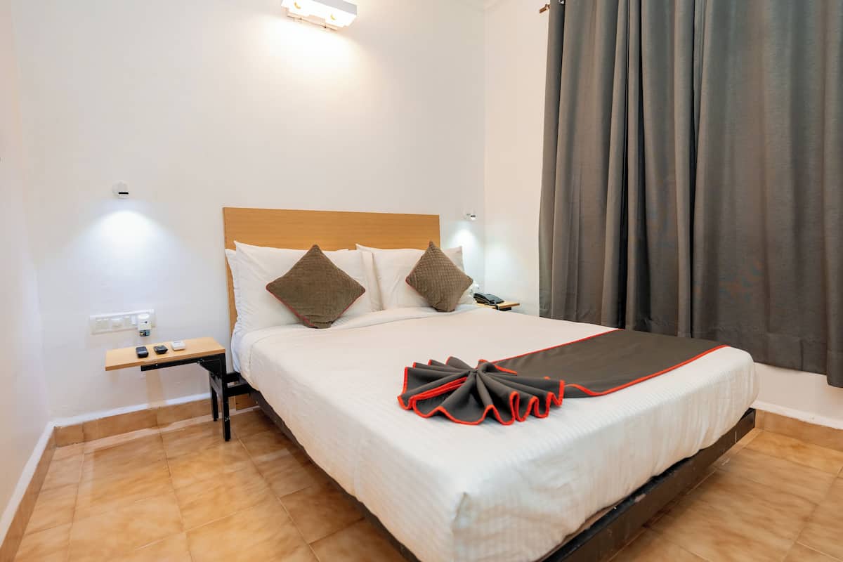 Una cama bien hecha con cabecera de madera, una mesita de noche con un teléfono y una lámpara de pared.