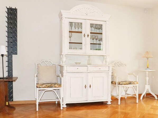 A white cabinet with glass doors, two white chairs with patterned cushions, and a small table with a lamp. - 8 Person Holiday Home in Bastad-by Traum (Bastad)