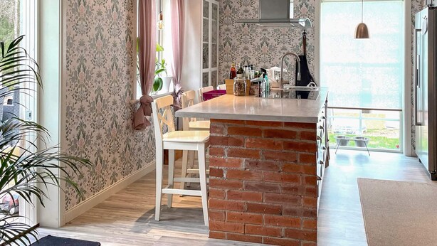 A kitchen with a brick island, wooden cabinets, a hanging light, and a view through the window. - 4 Star Holiday Home in Ulricehamn (Ulricehamn)