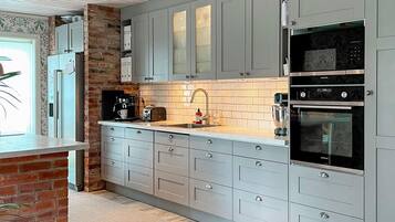 A modern kitchen with grey cabinets, a brick accent wall, a Siemens oven, and a coffee machine.