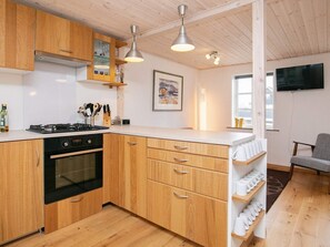 Enjoy cooking in this well-equipped kitchen with a sleek oven, stove, and flat-screen TV.