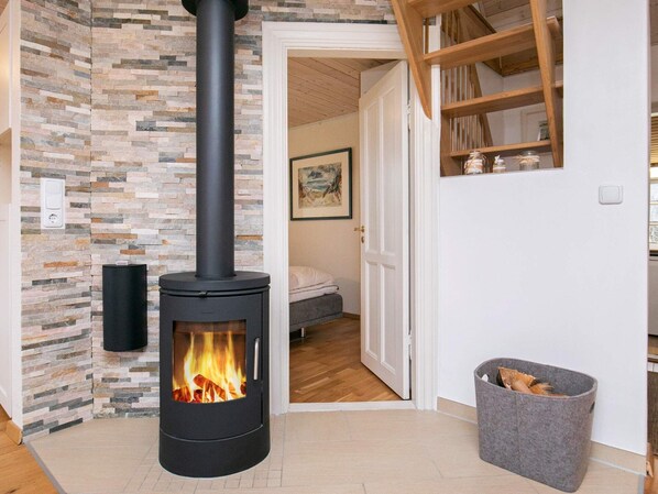 Cozy space with a central wood-burning stove and stone tile accent wall.