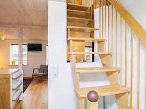 Staircase leads to an upper level, featuring a flat-screen TV and a cozy seating area.