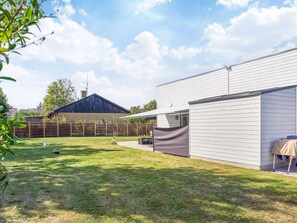 A residential backyard with a fenced area, a covered patio, and a house with a dark roof. - 4 Star Holiday Home in Nexo (Nexø)