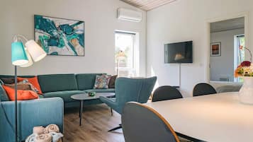 Una sala de estar moderna con sofá, sillas, una mesa de comedor y un televisor de pantalla plana.