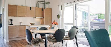 Una cocina moderna con armarios de madera, una mesa de comedor con sillas y vistas al exterior.