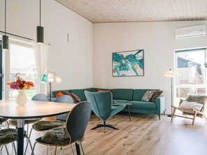 Un salon moderne avec un canapé vert, une table à manger ronde et un vase de fleurs.