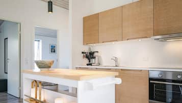 Una cocina moderna con armarios de madera, horno empotrado y encimera con un bol y velas.