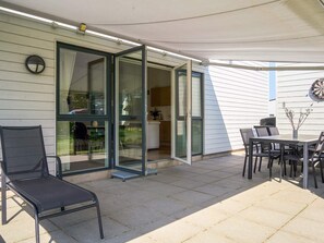 Une terrasse extérieure avec une table à manger, des chaises et un barbecue.