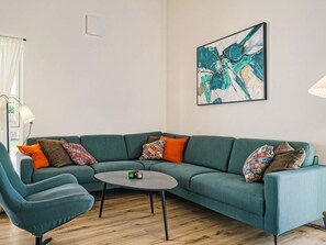 A modern living room with a teal sofa, a round coffee table, and colorful throw pillows. - 4 Star Holiday Home in Nexo (Nexø)