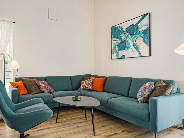 A modern living room with a teal sofa, a round coffee table, and colorful throw pillows.