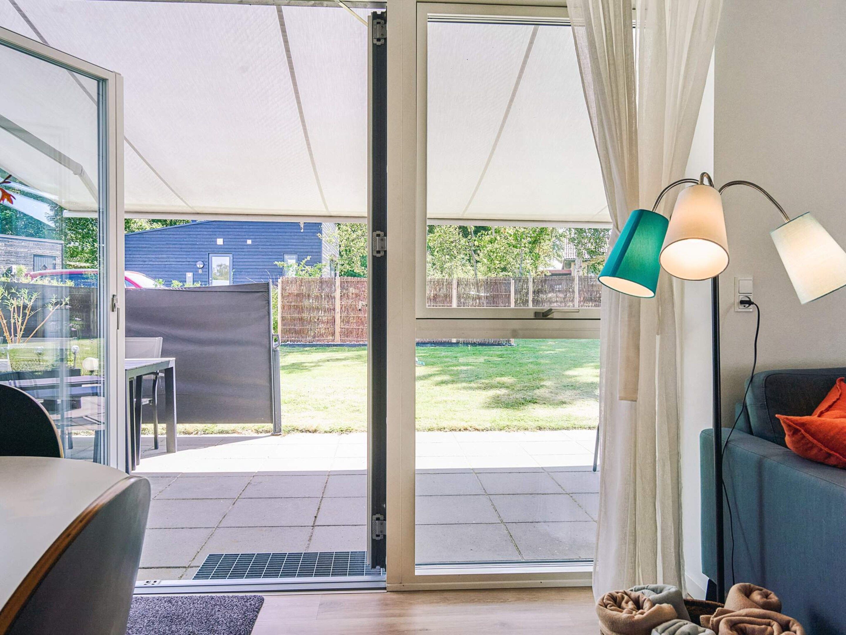 A room with a sliding glass door leading to a patio, a sofa, a lamp, and a chair.