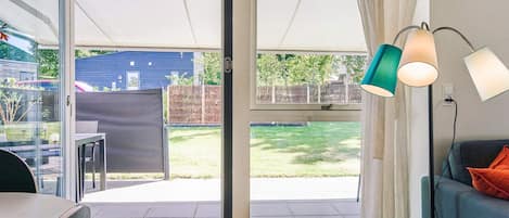 A room with a sliding glass door leading to a patio, a sofa, a lamp, and a chair.