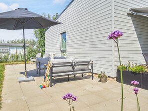 A patio with a bench, an umbrella, and outdoor furniture.