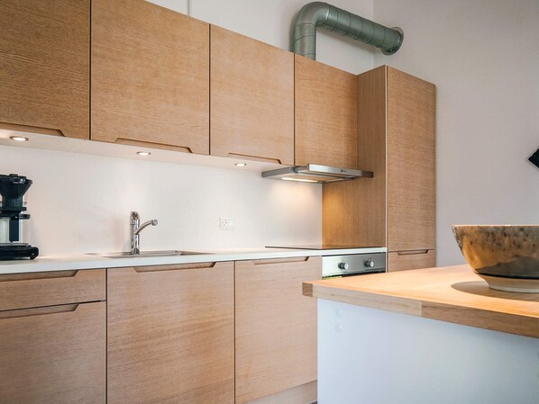 A modern kitchen with wooden cabinets, a stainless steel sink, and a coffee maker.