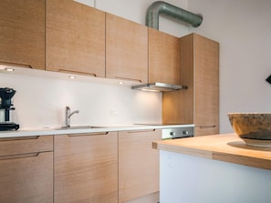 Una cocina moderna con armarios de madera, un lavamanos de acero inoxidable y una cafetera.