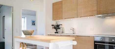 A modern kitchen with wooden cabinets, a built-in oven, and a central island with a bowl and candles.