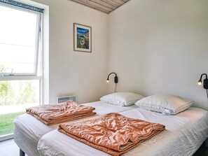 A bedroom with two beds, a window, a wall-mounted picture, and two wall sconces. - 4 Star Holiday Home in Nexo (Nexø)