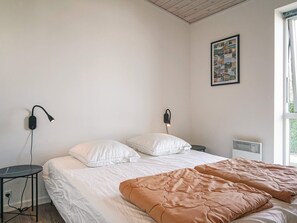 Une chambre à coucher comprenant un lit, deux tables de chevet, une lampe fixée au mur, un radiateur et un tableau encadré accroché au mur.