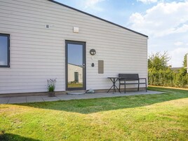 A modern building with a white exterior, a door, a small table, and a bench.