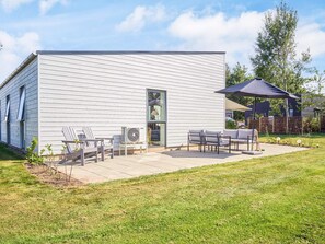 Une maison moderne dotée d’un patio aménagé avec des meubles d’extérieur et un ventilateur.