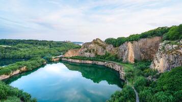 A natural landscape with a lake surrounded by cliffs and dense greenery.