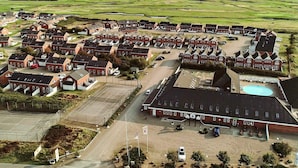A large, circular cluster of red-brick houses with a central building that includes a swimming pool. - 8 Person Holiday Home in Romo (Rømø)