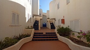 A narrow courtyard with a blue door at the end of a set of stairs, surrounded by white walls and plants. - Beachfront Home in La Isleta (La Isleta)