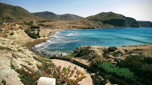 A coastal landscape with a rocky beach, clear blue sea, and mountainous terrain in the background. - Beachfront Home in La Isleta (La Isleta)